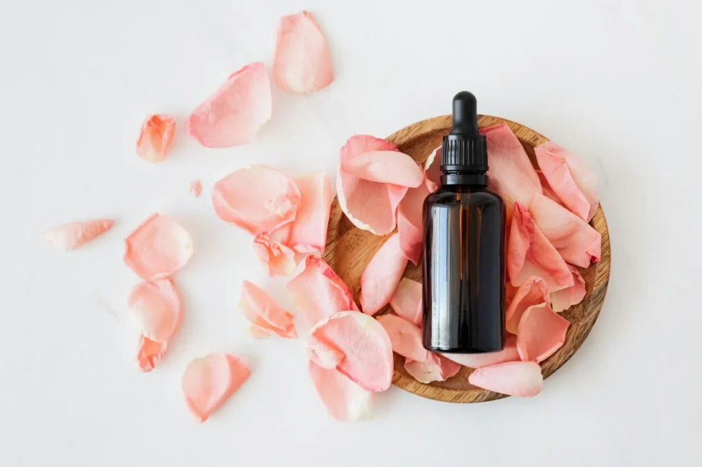 Flacon d'huile sur un support en bois et des pétales de rose