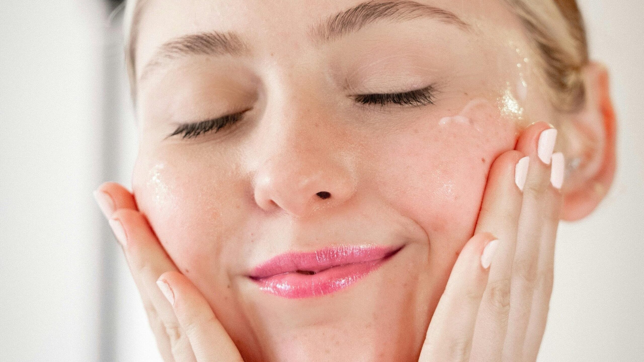 Femme souriante appliquant son soin visage