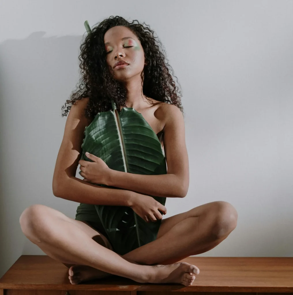 Femme assise qui ferme les yeux et tenant une feuille d'arbre